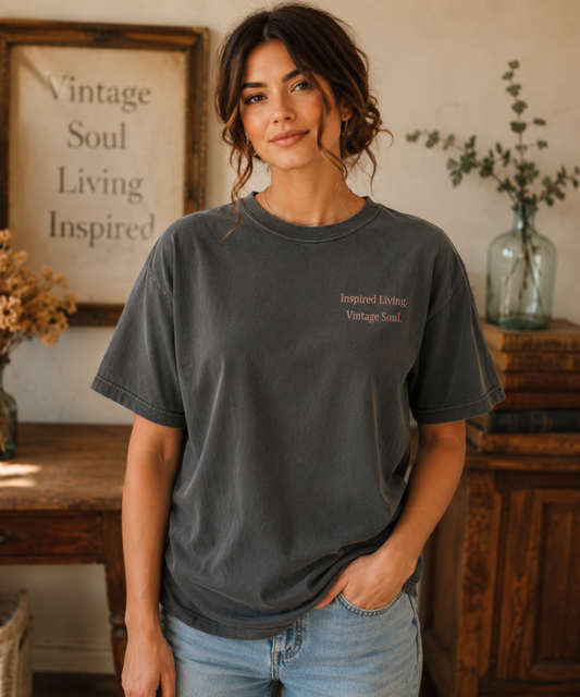 Woman wearing a Comfort Colors Graphite T-shirt featuring the Inspired Living. Vintage Soul. left chest design, styled in a warm vintage-inspired setting with a relaxed everyday look.