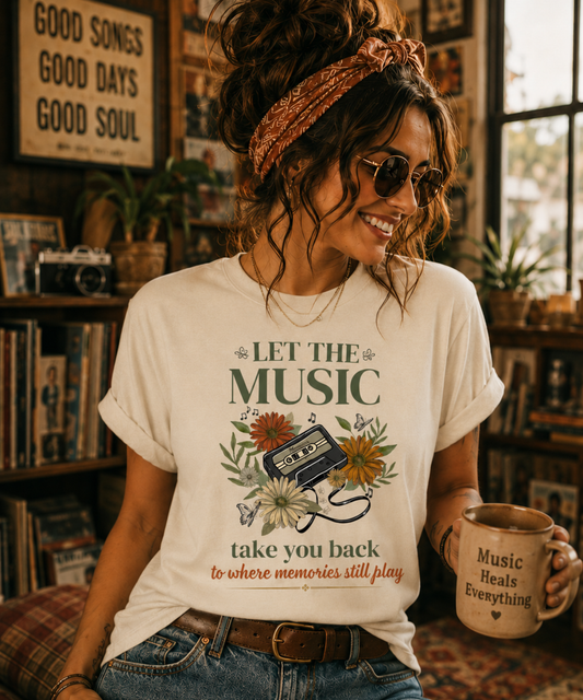 Woman in a cozy vintage-inspired music room wearing an ivory Comfort Colors 1717 t-shirt featuring a retro cassette tape, flowers, and the phrase "Let The Music Take You Back To Where Memories Still Play."