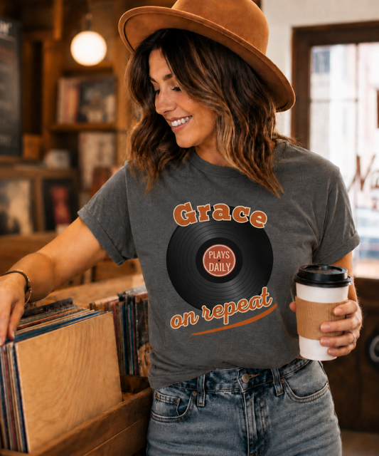 Woman wearing a vintage-style Grace on Repeat Christian graphic T-shirt featuring a retro vinyl record design while browsing records in a cozy record shop.