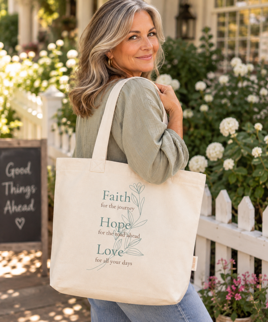 Woman carrying ivory Christian tote with Faith Hope Love botanical design in a warm garden setting