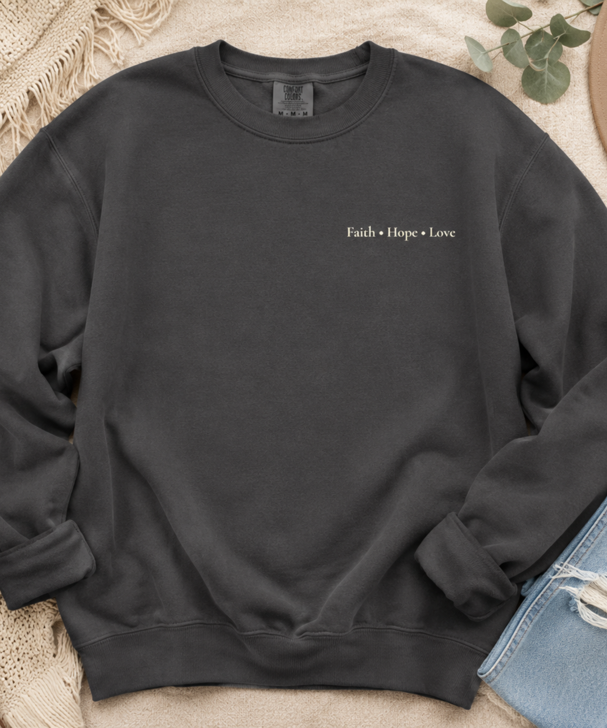 Flat lay of Comfort Colors pepper crewneck sweatshirt with Faith Hope Love left chest Christian design
