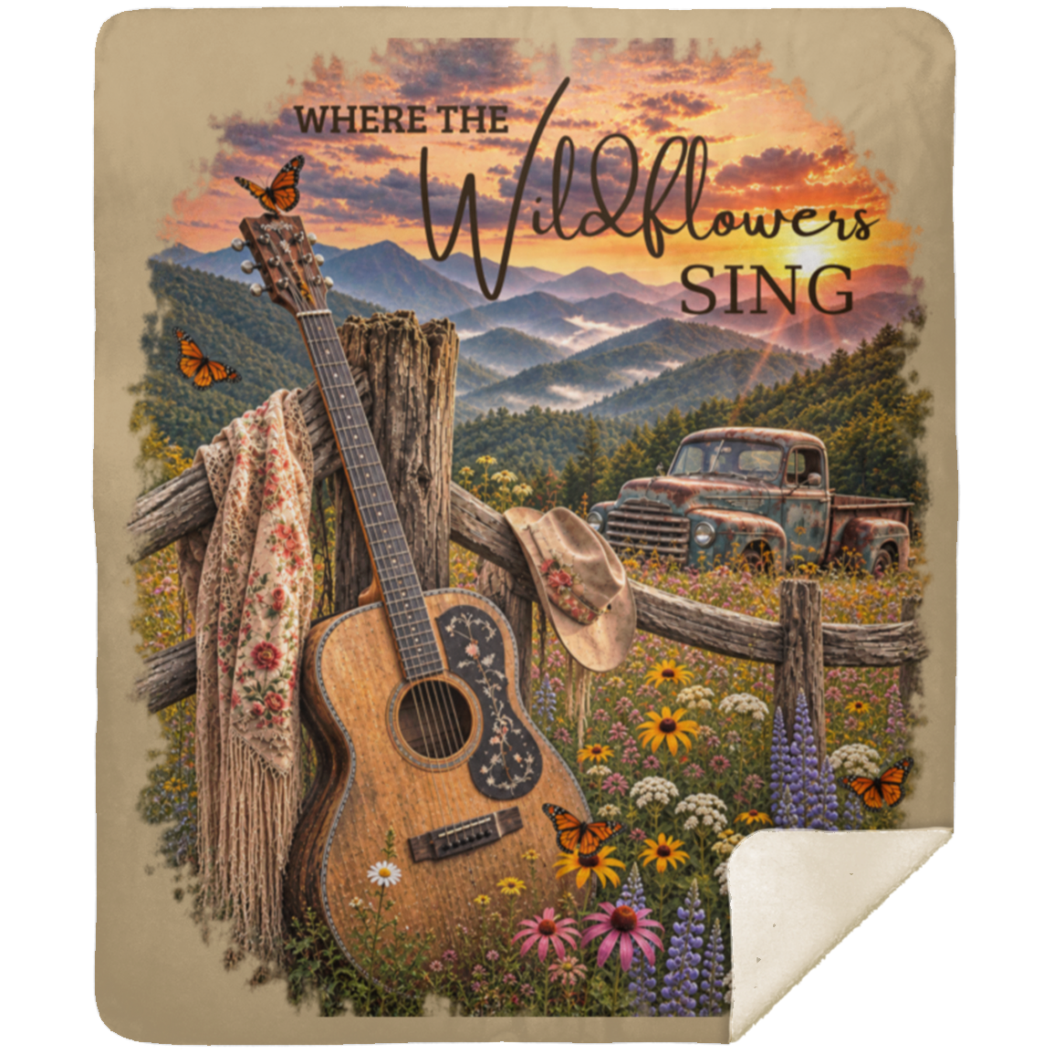 A sherpa fleece blanket with a rustic country design, featuring an acoustic guitar, a cowboy hat, mountains, a pickup truck, and the text 'WHERE THE Wildflowers SING'. The blanket has a tan border and a cream-colored reverse side with a curled corner, shown against a plain white background.