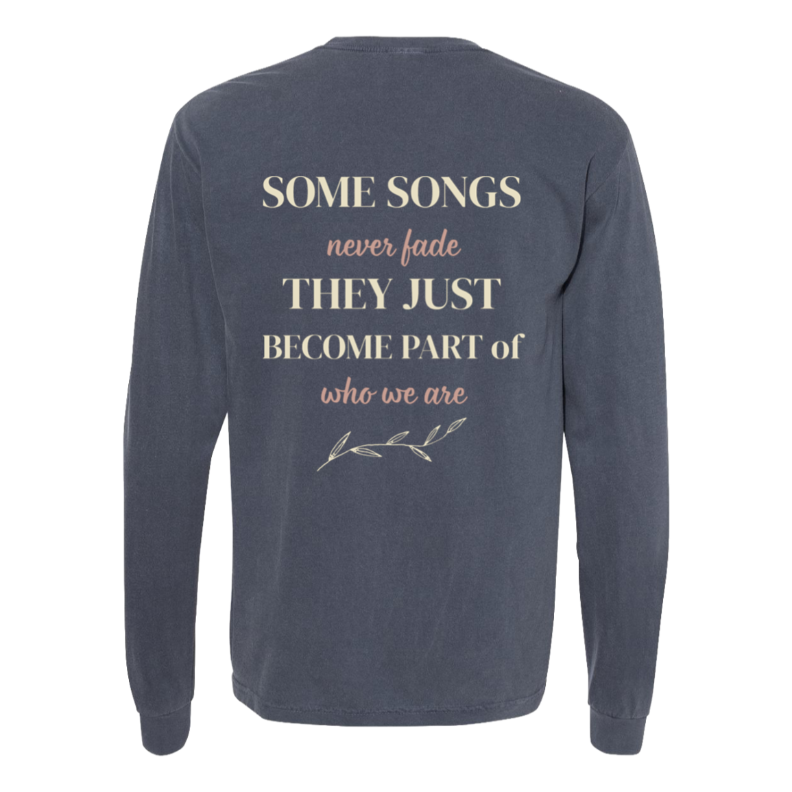 A denim comfort colors long-sleeve t-shirt shown from the back, featuring a printed quote in cream and dusty pink text that reads 'SOME SONGS never fade THEY JUST BECOME PART of who we are' with a small branch illustration.