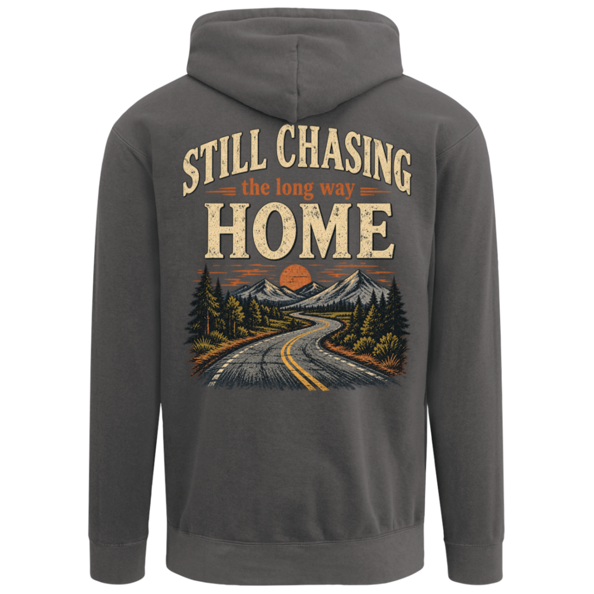 A pepper comfort colors hoodie shown from the back, featuring a large graphic print of a winding road through pine trees toward mountains at sunset, with the text 'STILL CHASING the long way HOME'. Includes left chest design