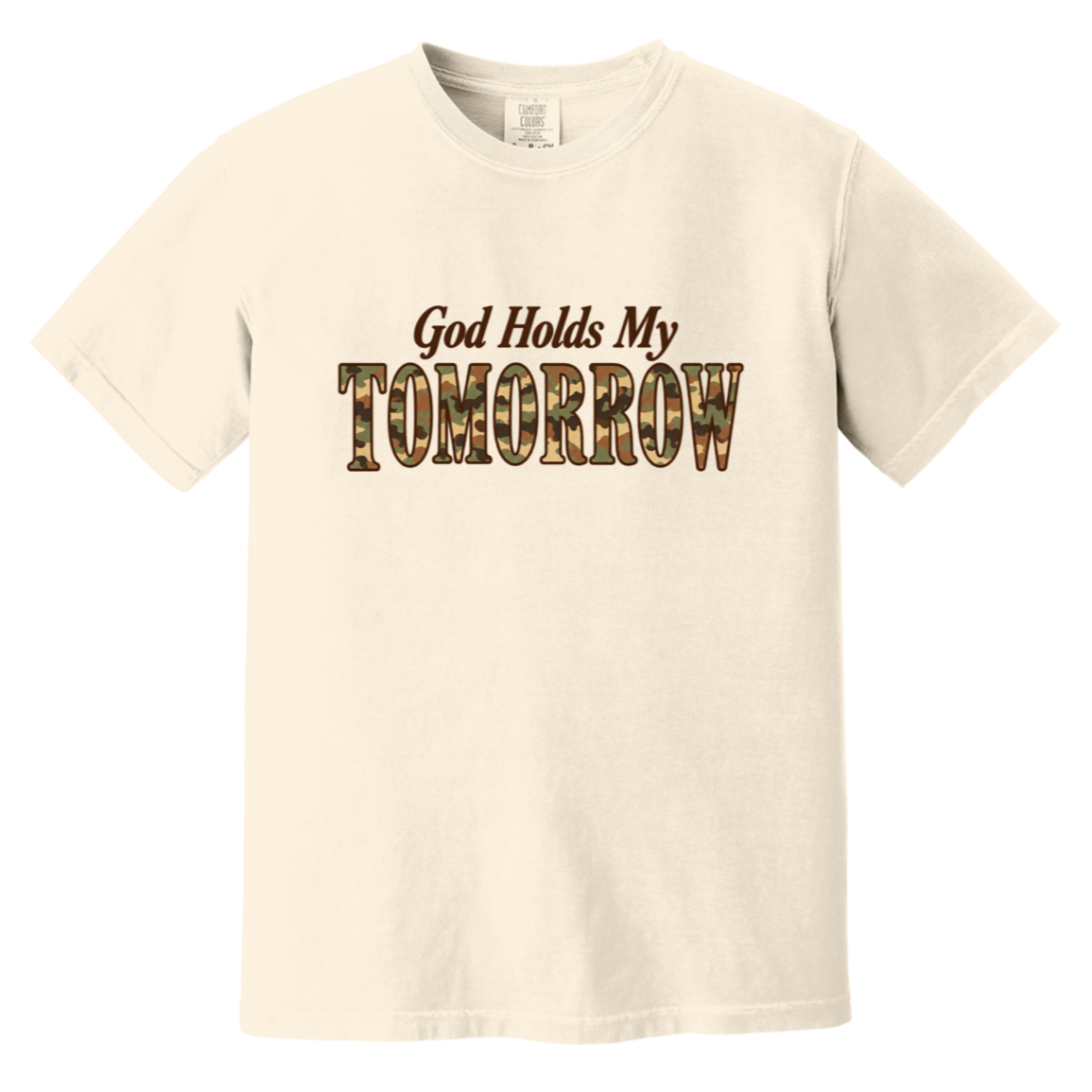 An ivory comfort colors t-shirt with the text 'God Holds My TOMORROW' printed on the chest. The word 'TOMORROW' is filled with a camouflage pattern, while 'God Holds My' is in a dark brown serif font.