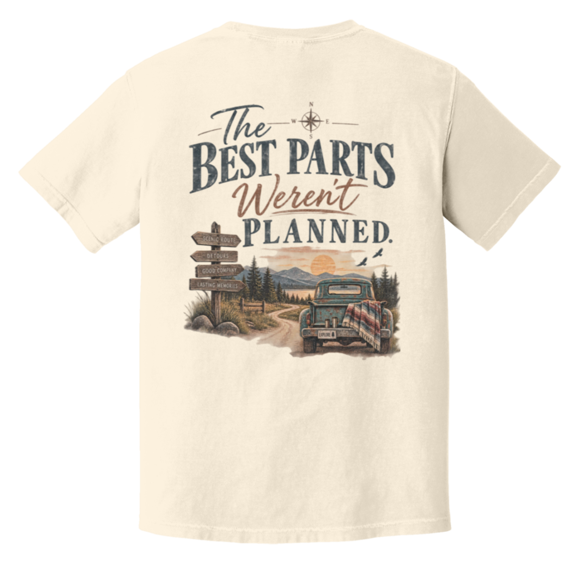 An ivory comfort colors short-sleeve t-shirt shown from the back, featuring a large graphic print with the text 'The BEST PARTS Weren't PLANNED.' above an illustration of a vintage car on a dirt road with a signpost.
