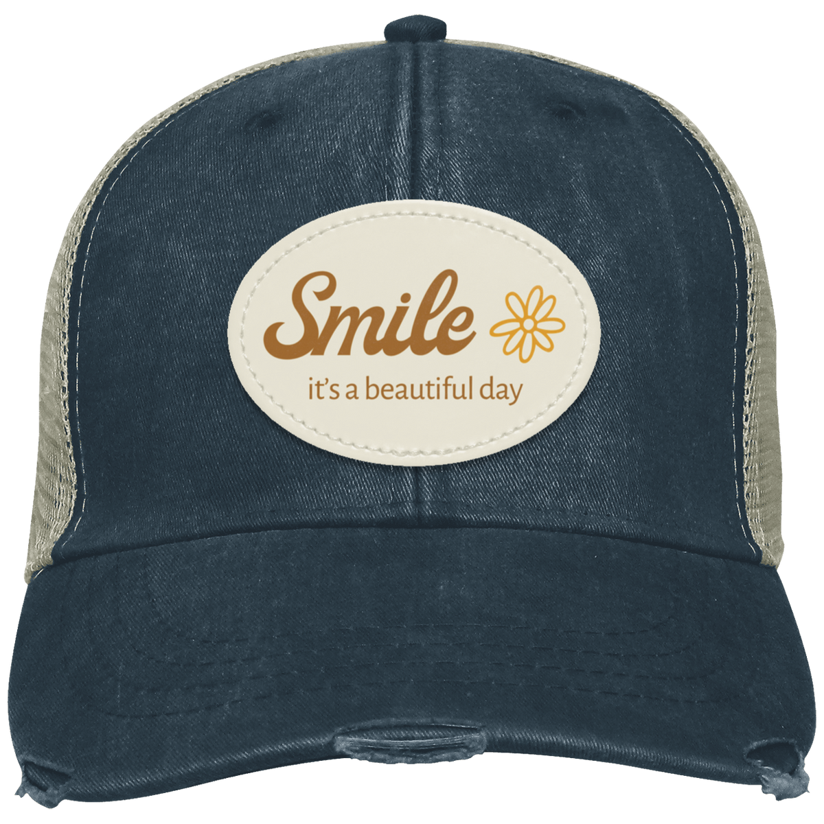 A distressed trucker hat in washed navy with tan mesh side panels. The front features a cream-colored oval patch with the text 'Smile it's a beautiful day' in brown lettering and a small yellow flower graphic.