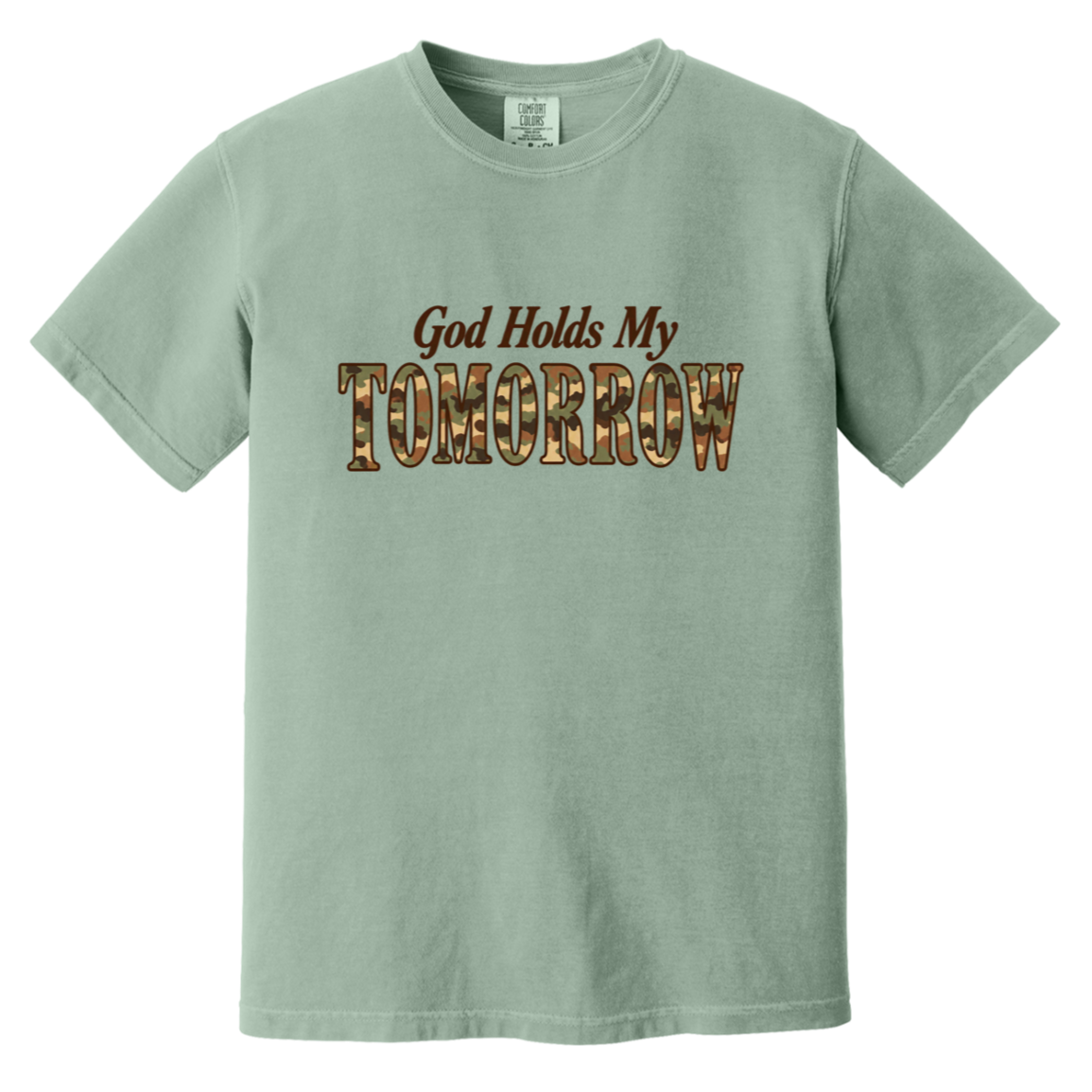 A bay green comfort colors t-shirt with the text 'God Holds My TOMORROW' printed on the chest. The word 'TOMORROW' is filled with a camouflage pattern, while 'God Holds My' is in a dark brown serif font.