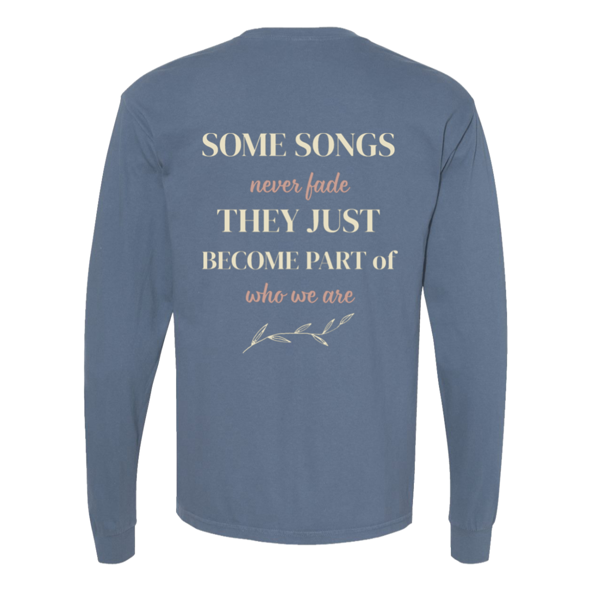 A long-sleeve t-shirt in blue jean comfor colors, shown from the back. The back features a printed quote in cream and peach lettering that reads 'SOME SONGS never fade THEY JUST BECOME PART of who we are' with a small leafy branch illustration underneath.