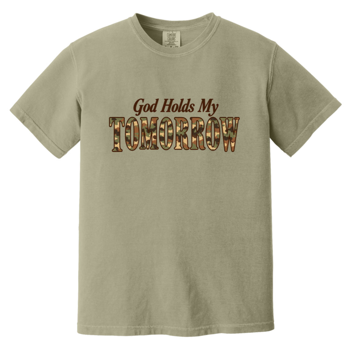 A khaki comfort colors short-sleeve t-shirt with a graphic on the chest that reads 'God Holds My TOMORROW' in brown and camouflage lettering, displayed on a solid white background.