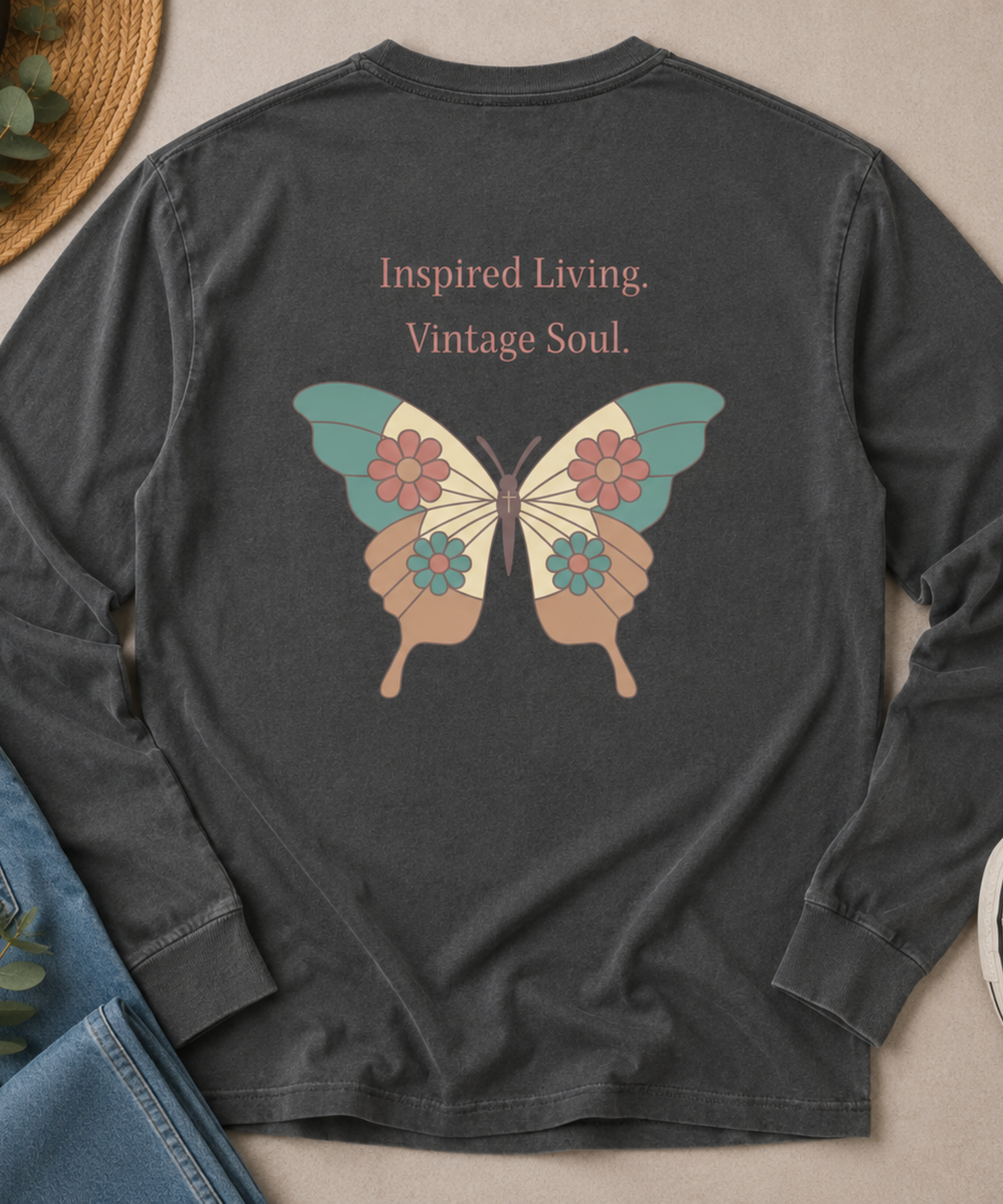 Flat lay of a Comfort Colors Pepper long sleeve T-shirt featuring the Inspired Living. Vintage Soul. butterfly back design, styled with blue jeans, canvas sneakers, and a straw hat.