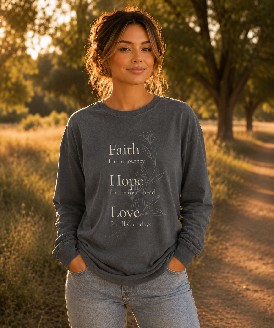 Comfort Colors pepper long sleeve shirt worn outdoors featuring Faith Hope Love botanical Christian design on the front in a warm vintage nature setting.