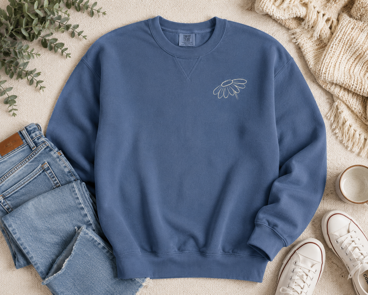 Flat lay of Comfort Colors Blue Jean crewneck sweatshirt with wildflower left chest design and casual denim styling