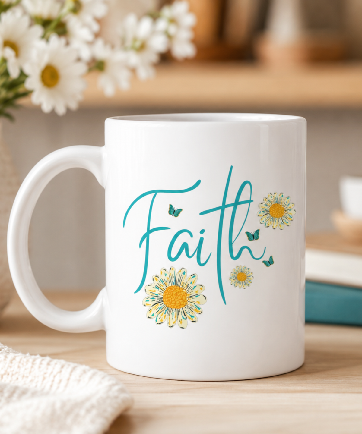 A white ceramic coffee mug with the word 'Faith' written in teal script, decorated with yellow and white daisy flowers and small teal butterflies, sitting on a wooden table with a blurred background of flowers and books.