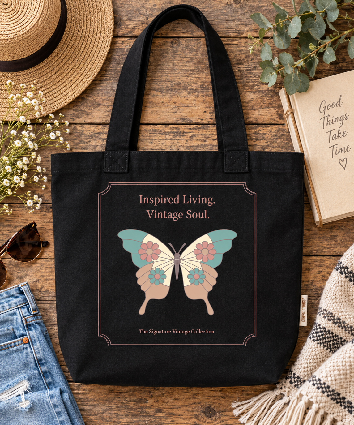 A black canvas tote bag with a vintage-style butterfly graphic and the text 'Inspired Living. Vintage Soul.