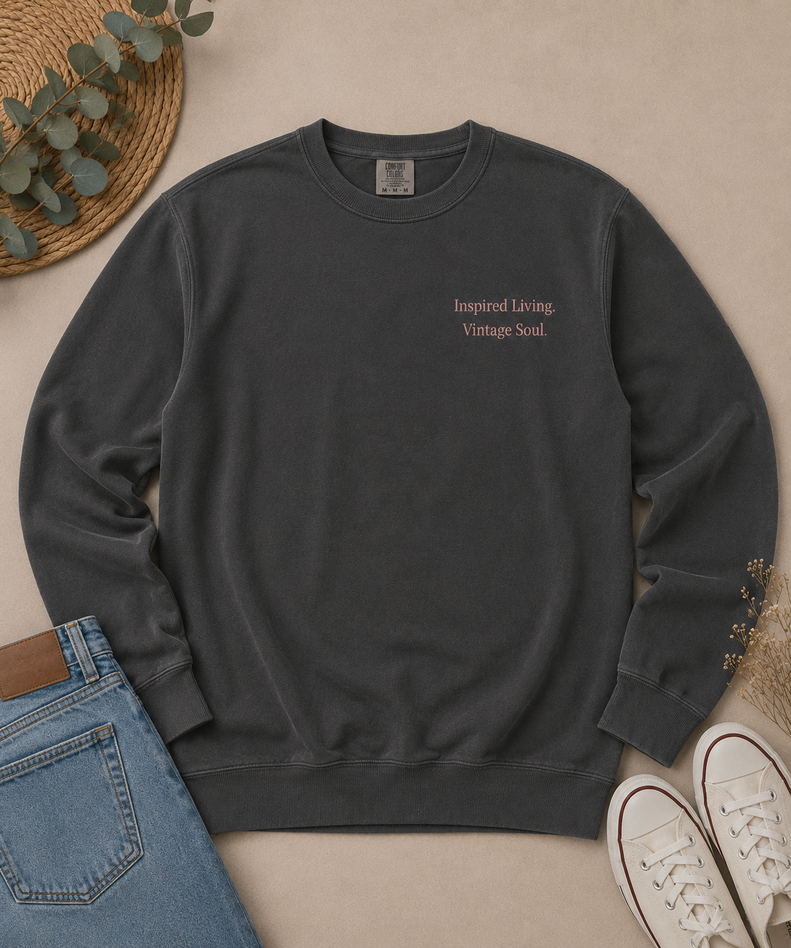 Flat lay of a Comfort Colors Pepper crewneck sweatshirt with the small left chest Inspired Living. Vintage Soul. design, styled with blue jeans, canvas sneakers, and natural accents.